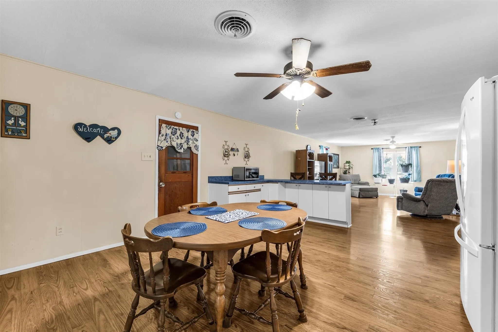 Wood-finish flooring throughout, white cabinetry, and a ceiling fan with integrated lighting