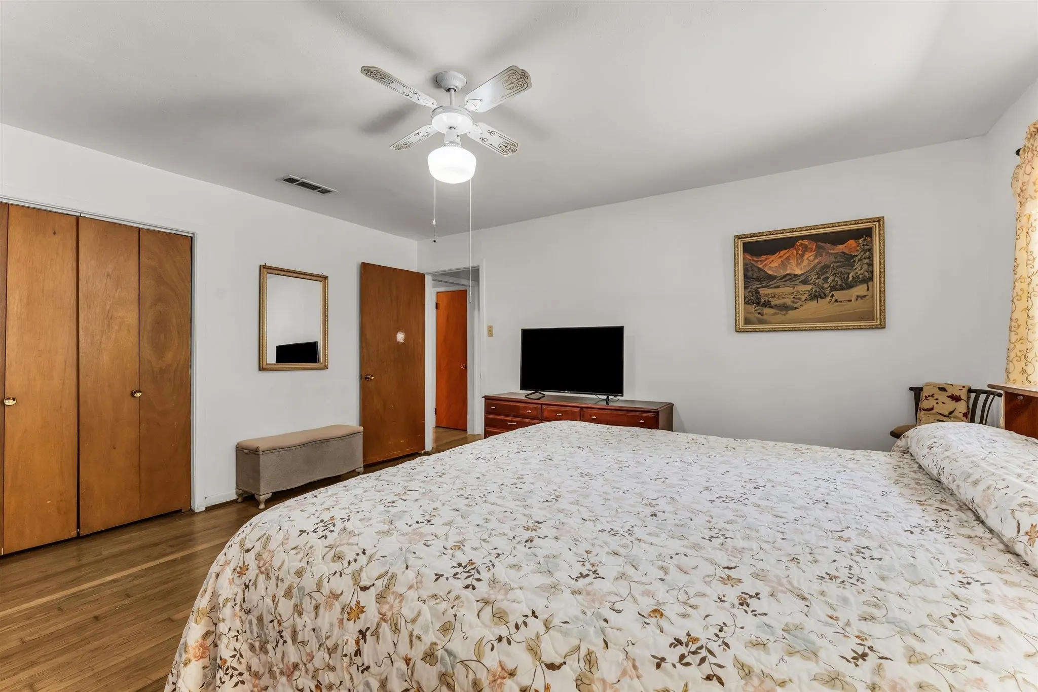 Light-colored wood-finish flooring with white walls and a ceiling fan