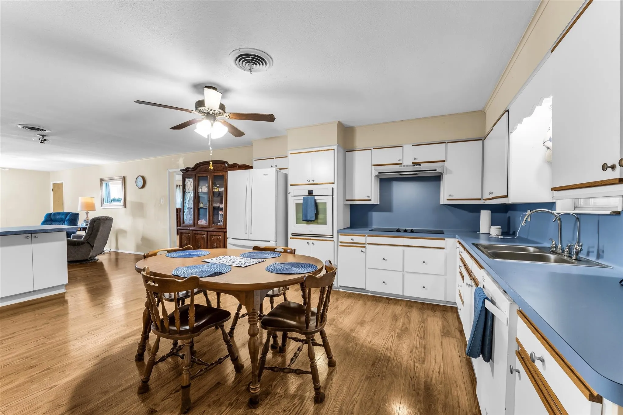 Kitchen with wood-finish flooring, white cabinetry, integrated wall oven, and a built-in cooktop