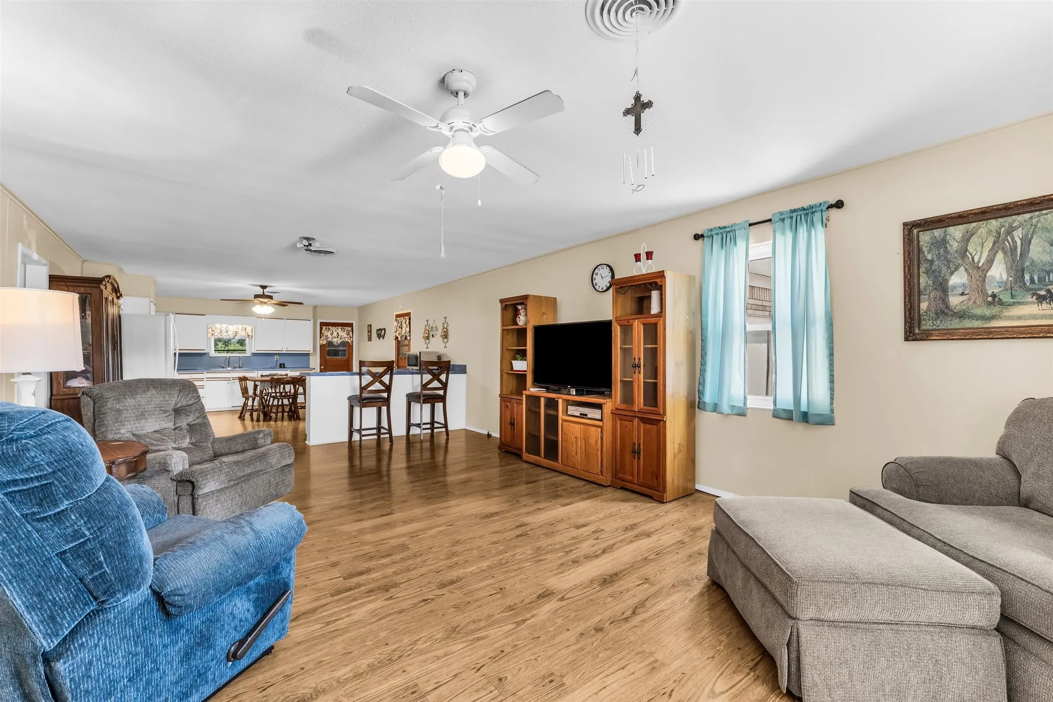 Open-concept living space with wood-finish flooring, ceiling fans, and neutral wall tones