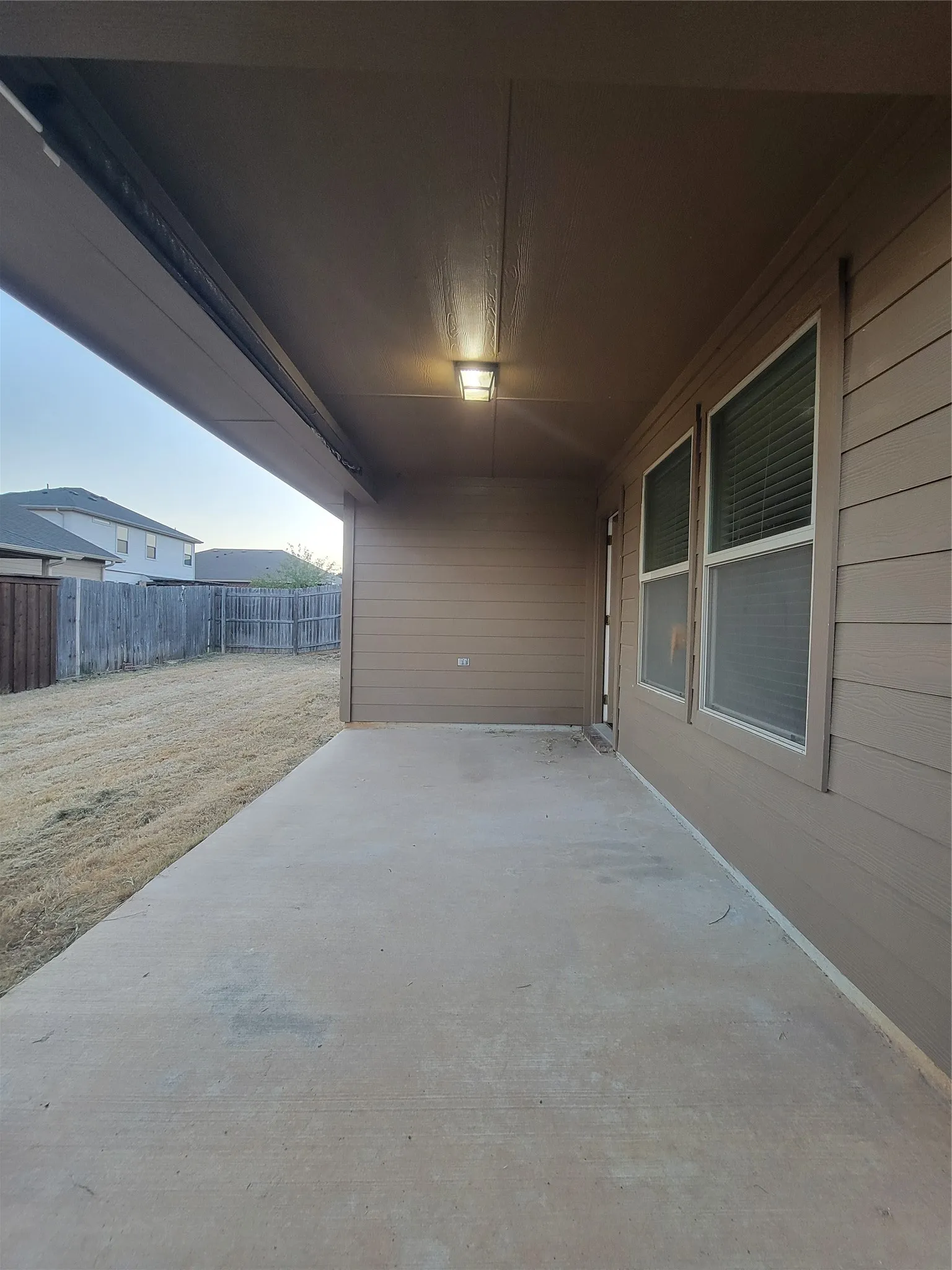 Covered patio with a concrete surface, exterior lighting, vinyl siding, and white-framed windows