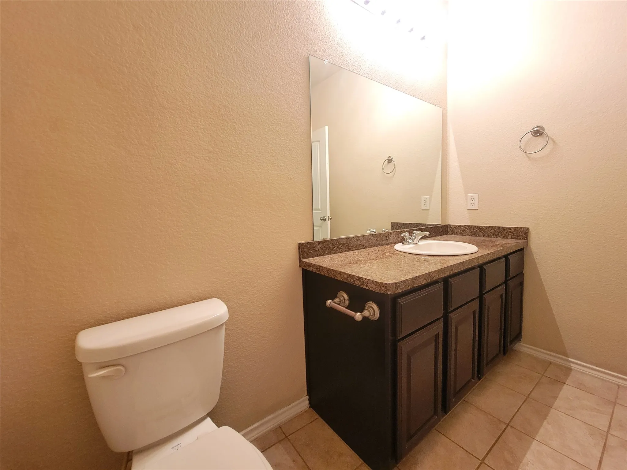 Vanity with a built-in sink, dark cabinetry, and speckled countertop