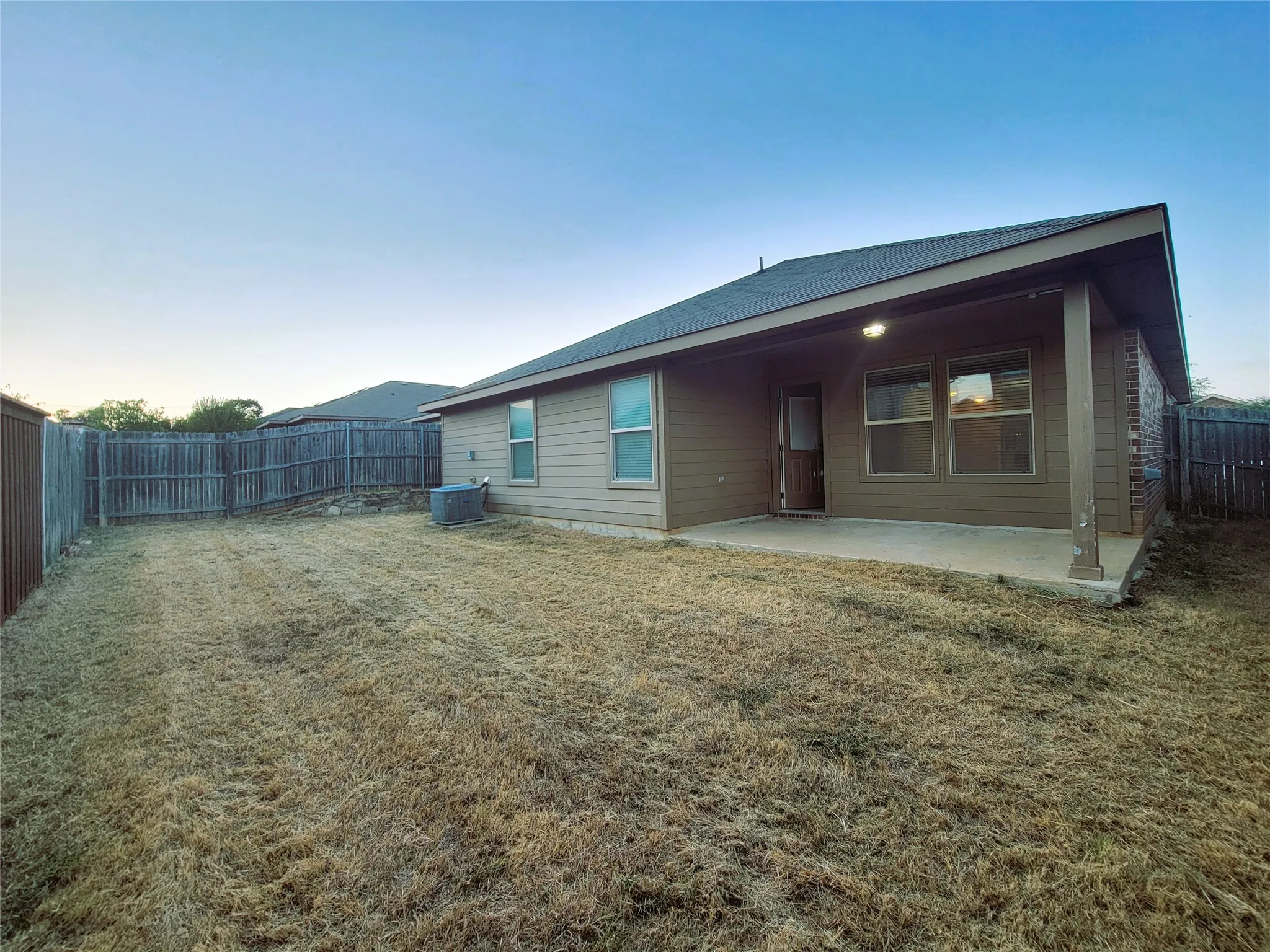 Covered patio with an exterior light fixture, concrete flooring, and a fenced yard