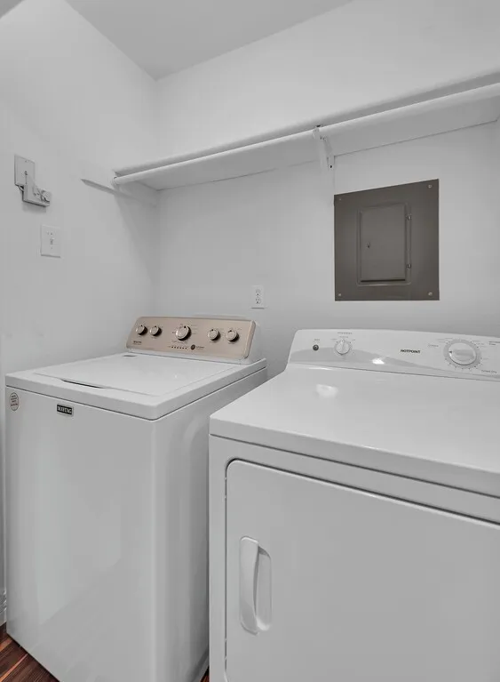 Laundry area featuring a built-in shelving unit and wood-finish flooring