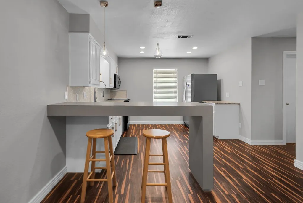 Kitchen featuring a breakfast bar, recessed lighting, wood-finish flooring, white cabinetry, and a tile backsplash