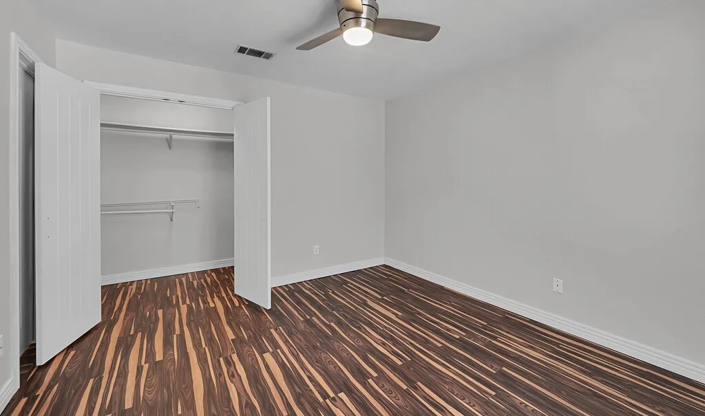 Wood-finish flooring, light gray wall paint, and a ceiling fan with brushed nickel accents