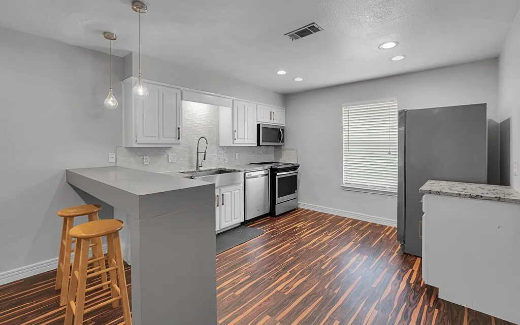 Kitchen featuring wood-finish flooring, white cabinetry, a built-in microwave, stainless steel appliances, and recessed lighting