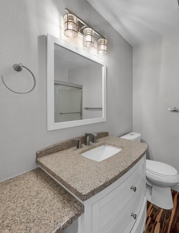 White vanity with curved drawer fronts, integrated sink, and speckled countertop