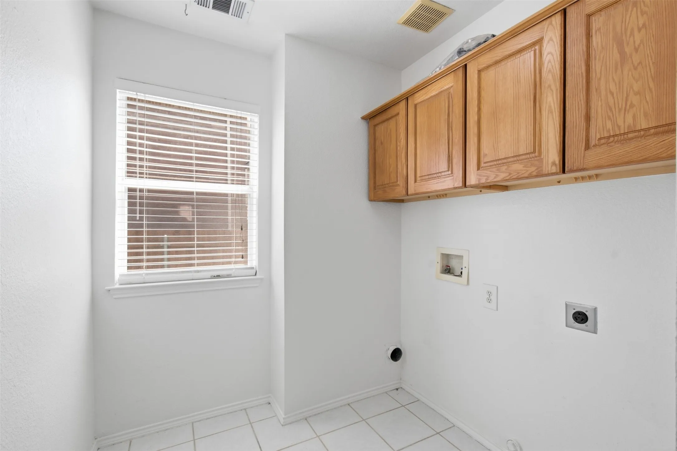 Large utility room featuring ample built-in storage solutions and a window that fills the area with bright, natural light.