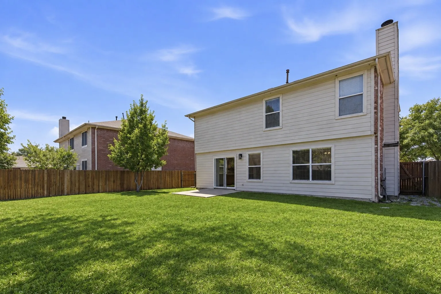 Spacious backyard featuring a patio and lush landscaping, perfect for entertaining and outdoor activities.