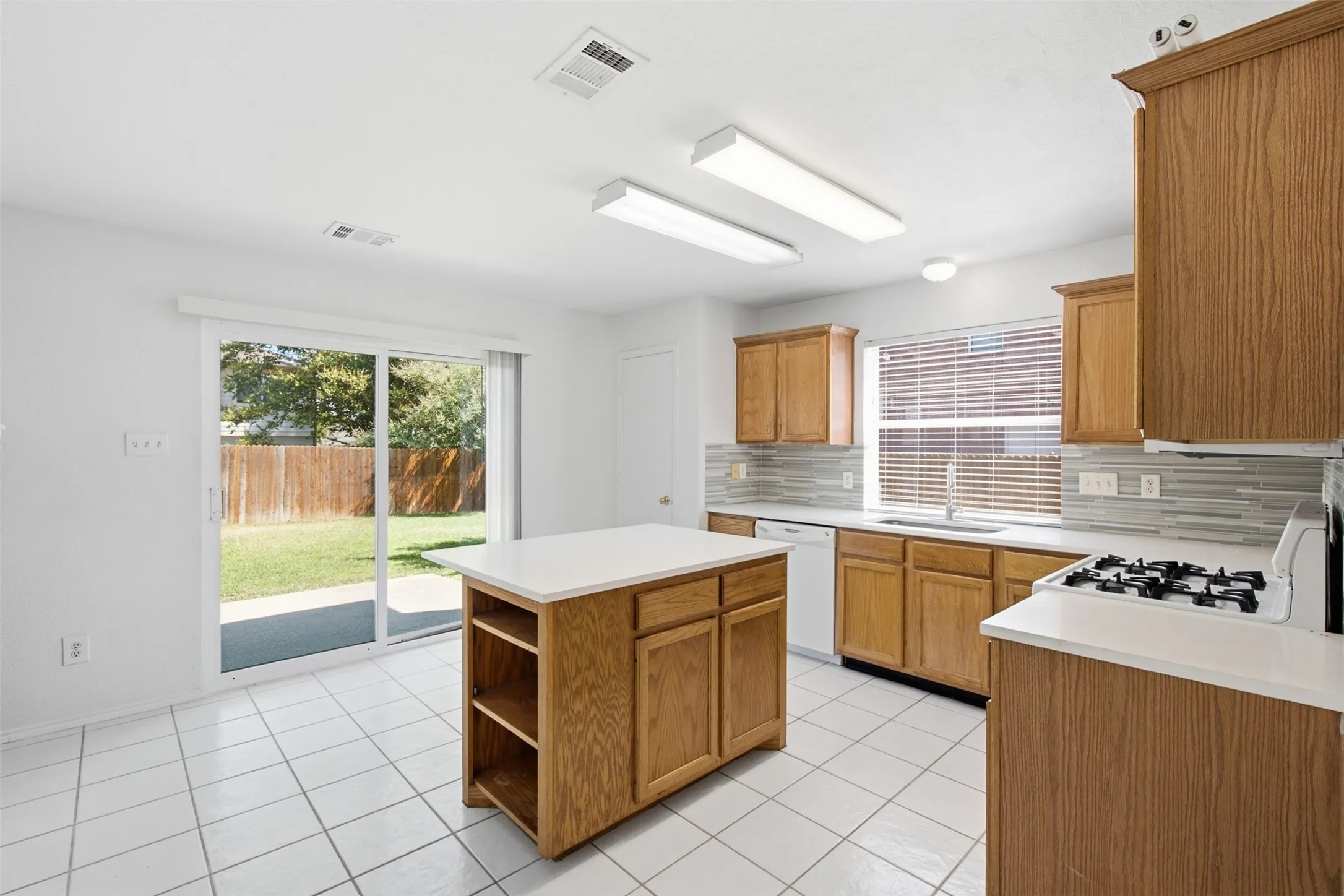 This kitchen is flooded with beautiful, warm natural light pouring in from the oversized sliding glass back door and the charming window positioned perfectly above the kitchen sink, creating an inviting and airy atmosphere that is sure to impress every potential buyer.