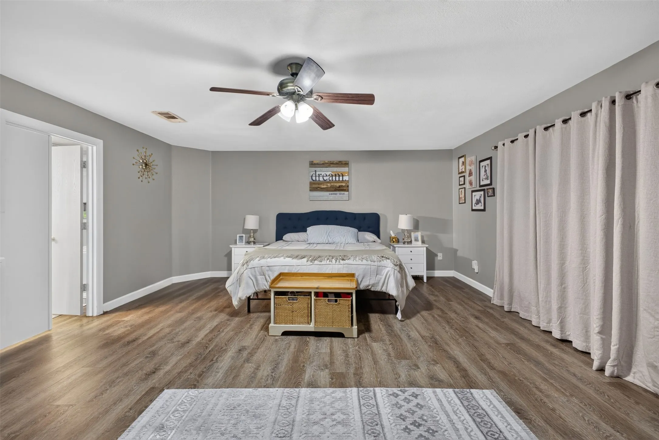Spacious room featuring wood-finish flooring, light gray walls, and a ceiling fan