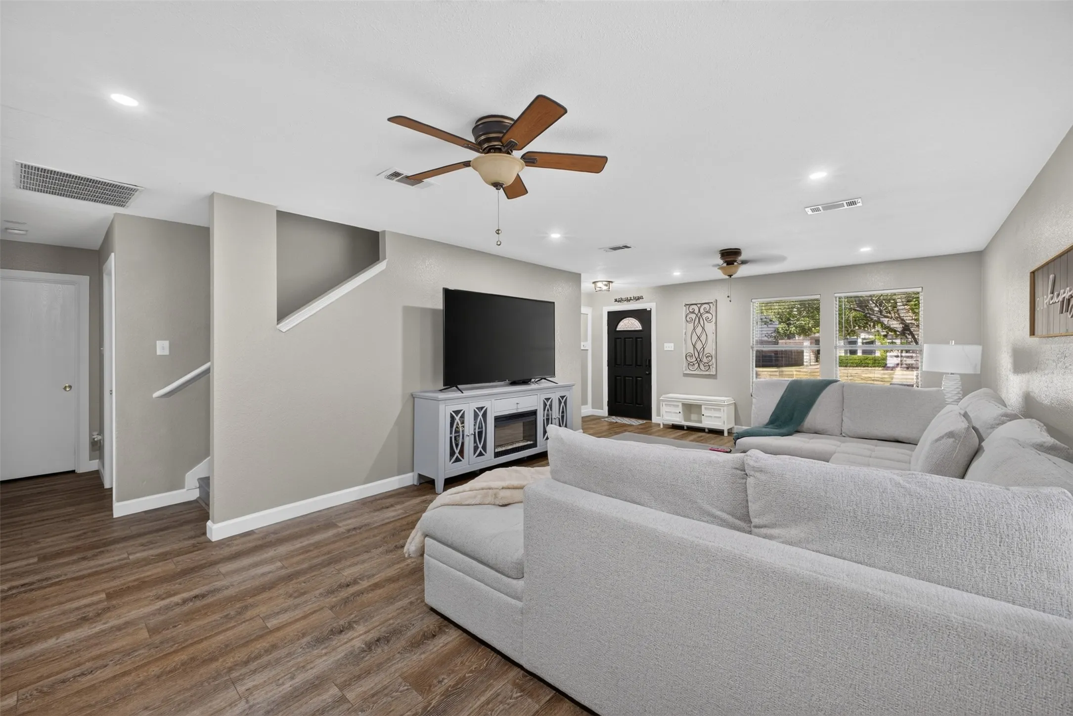 Wood-finish flooring throughout, complemented by recessed lighting and ceiling fans