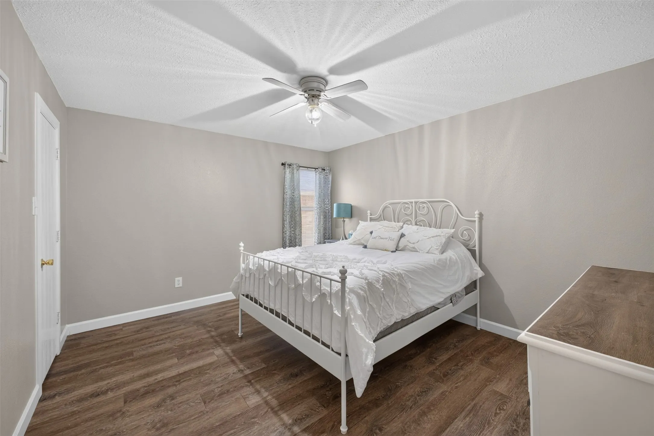 Ceiling fan with integrated lighting, wood-finish flooring, neutral wall tones, white trim, and a white interior door