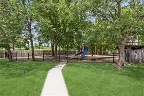 Manicured lawn with a concrete pathway leading to a fenced playground area