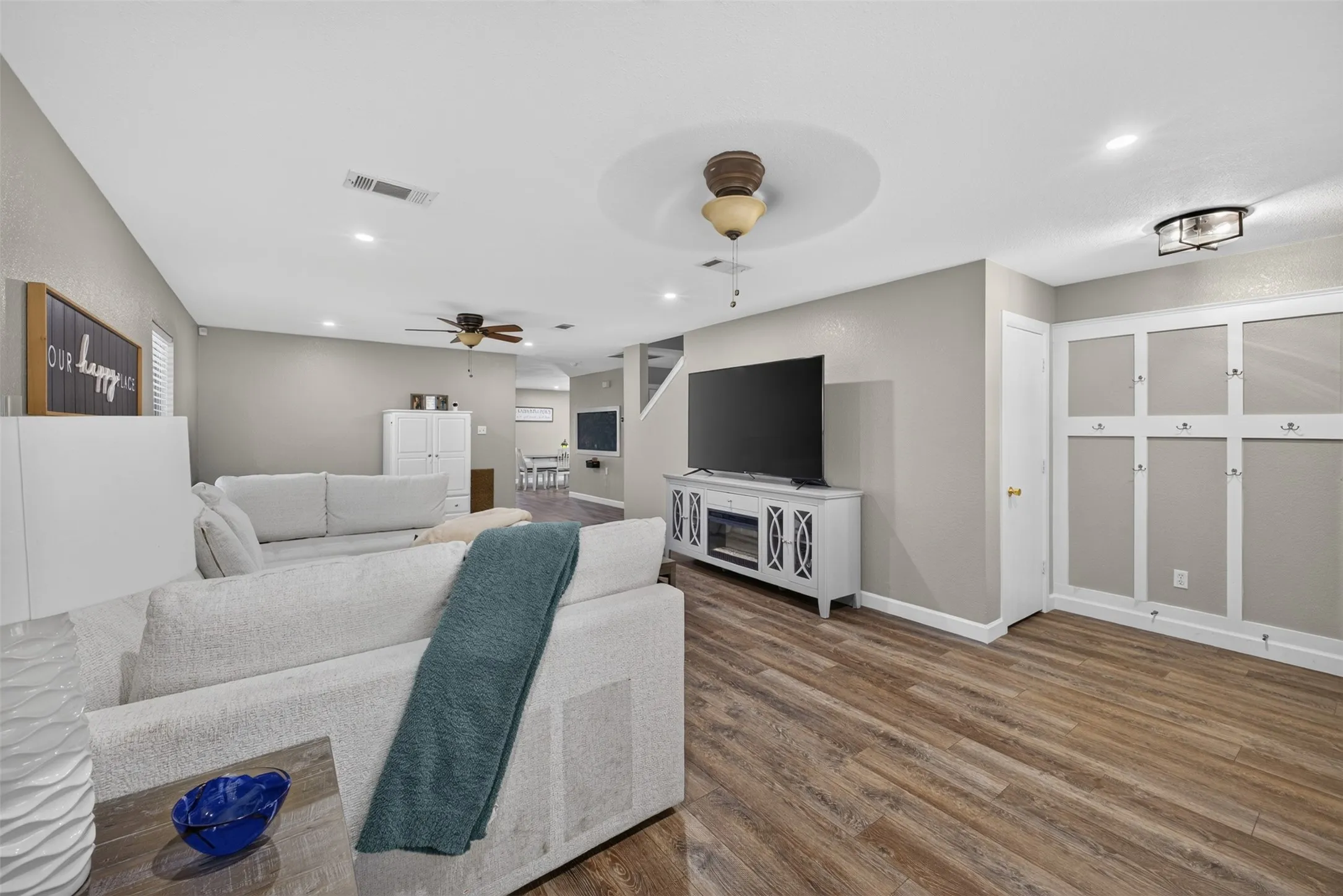 Wood-finish flooring, recessed lighting, ceiling fan with light fixture, decorative ceiling medallion, and a built-in wall feature with hooks