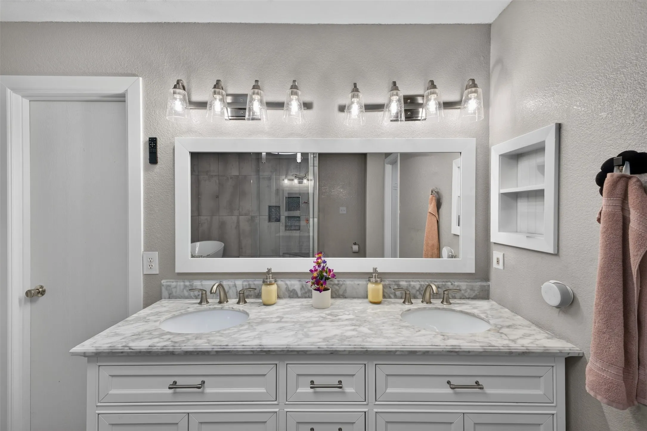 Dual undermount sinks with brushed nickel fixtures, a framed mirror, and a built-in wall niche