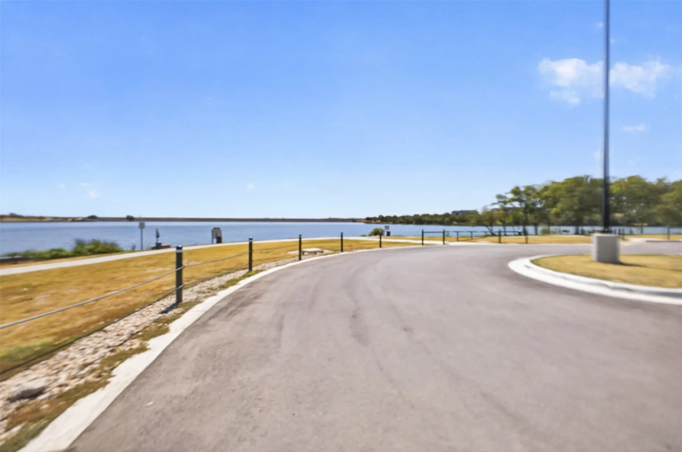 Paved curving roadway with a clear water backdrop