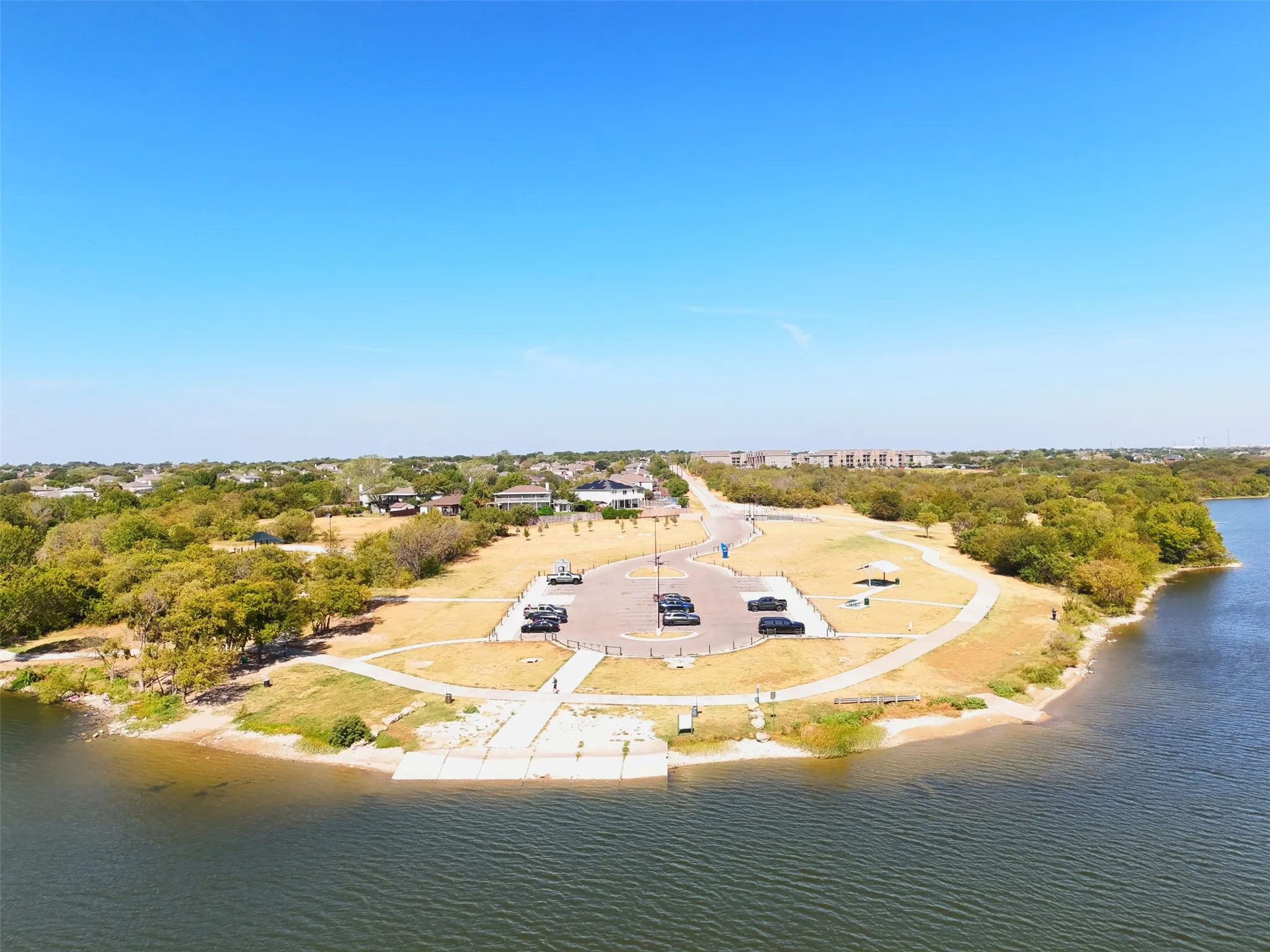Waterfront property with a boat ramp, concrete dock, and adjacent parking