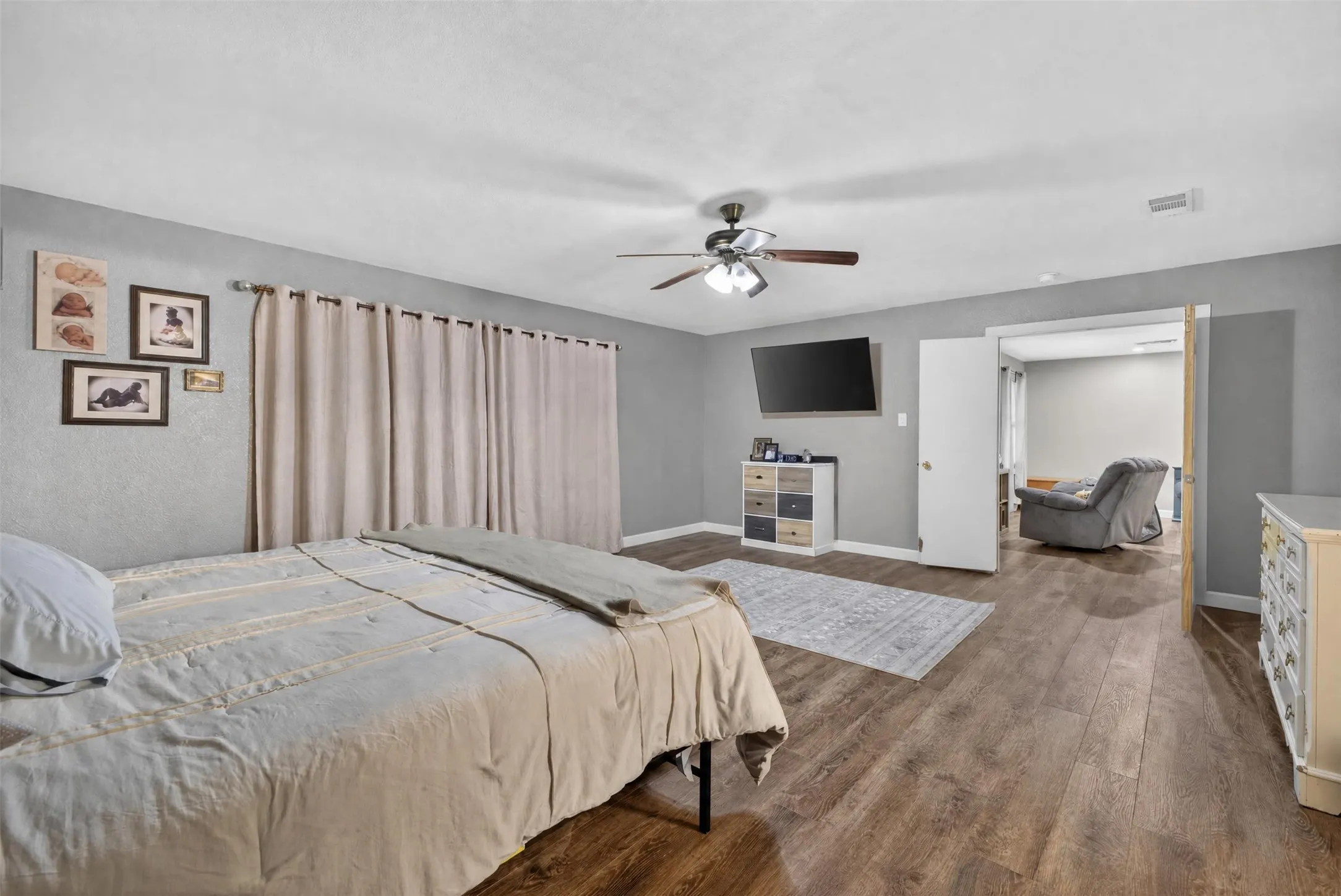 Wood-finish flooring, ceiling fan with integrated lighting, neutral wall tones, and recessed doorway