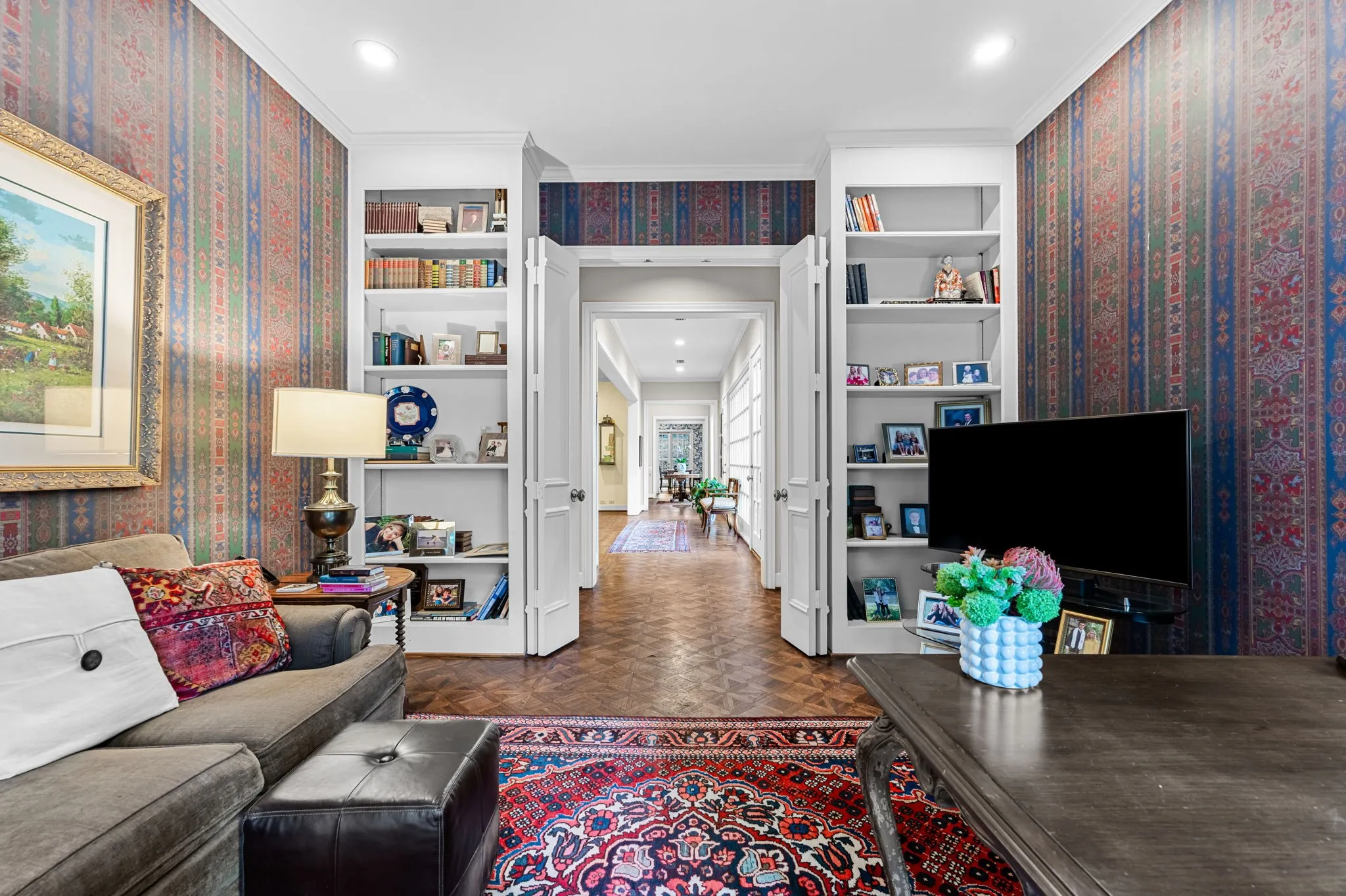 Built-in shelving flanking a wide entry, recessed ceiling lighting, and wood-finish flooring