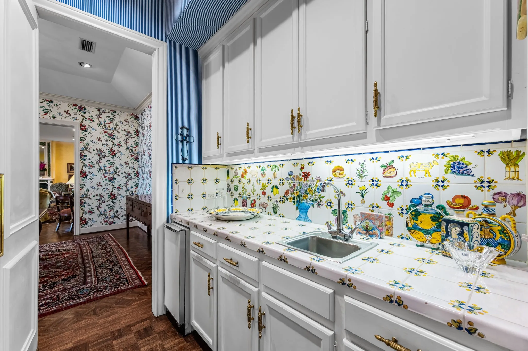 Butlers Pantry with white cabinetry with brass hardware, tile countertop, tile backsplash, and stainless steel sink