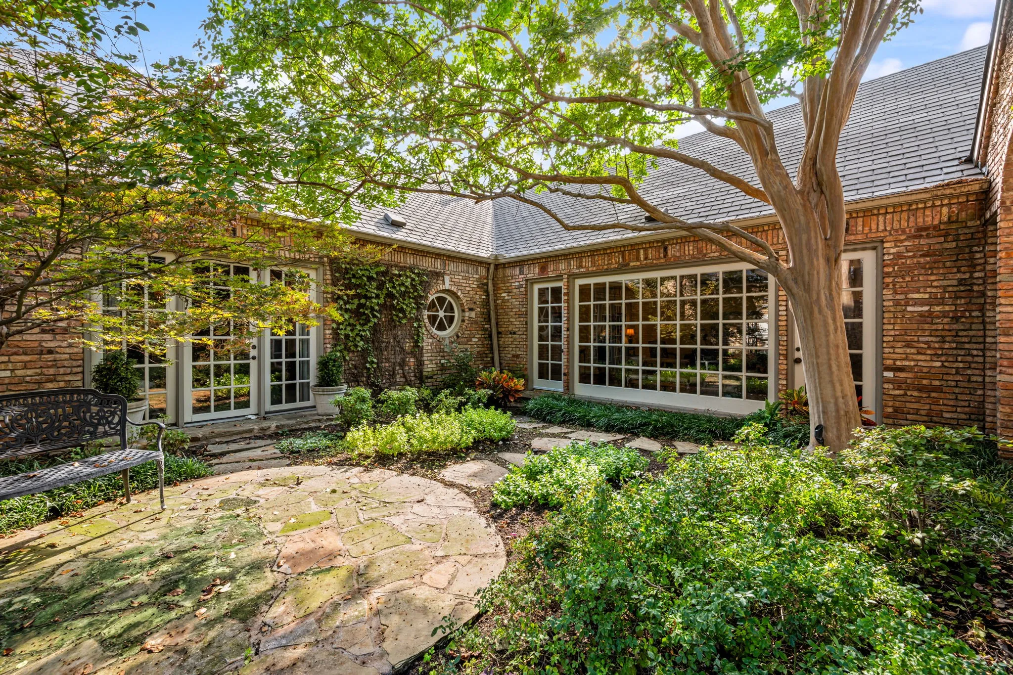 Brick exterior with large grid-pattern windows, circular porthole window, and French patio doors