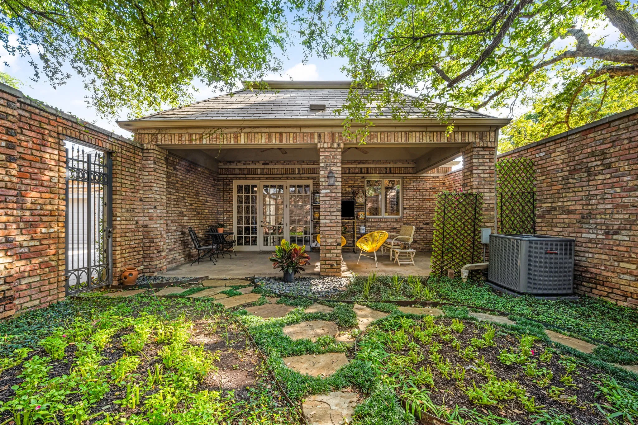 Covered patio with brick columns and French doors opening to an outdoor area with stepping stones
