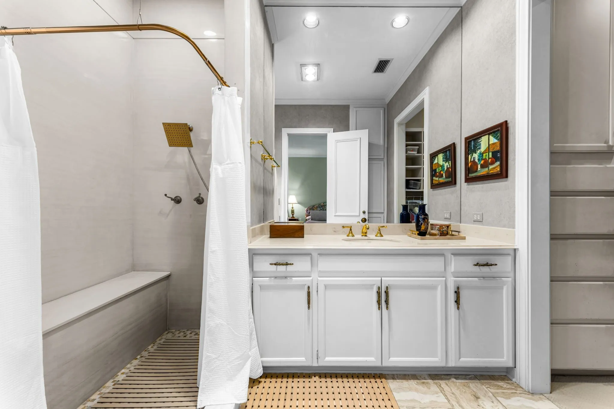 White vanity with integrated sink, gold-finish fixtures, and a large wall-mounted mirror
