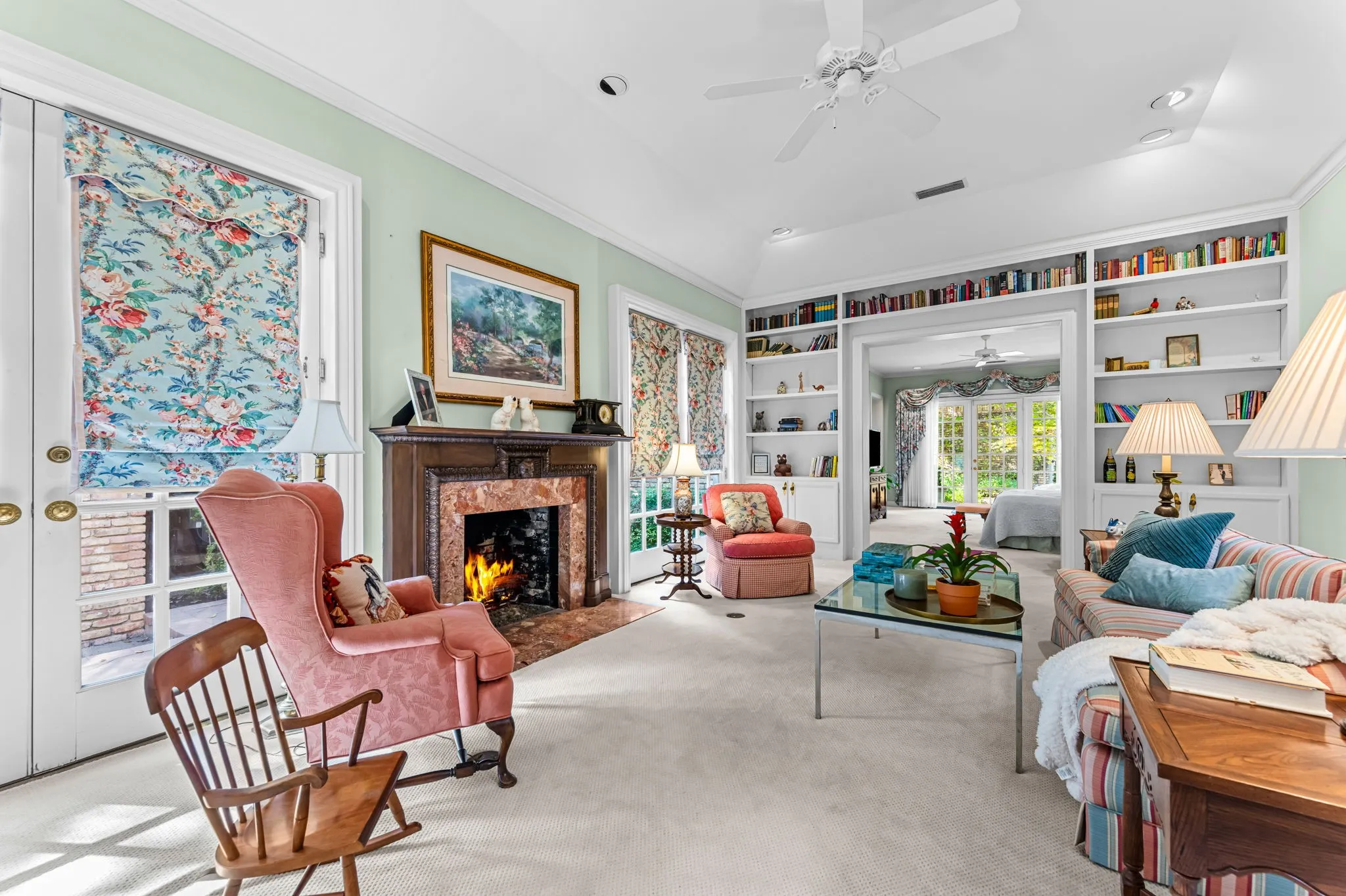 Recessed lighting, ceiling fan, built-in shelving, fireplace with stone surround, and French doors
