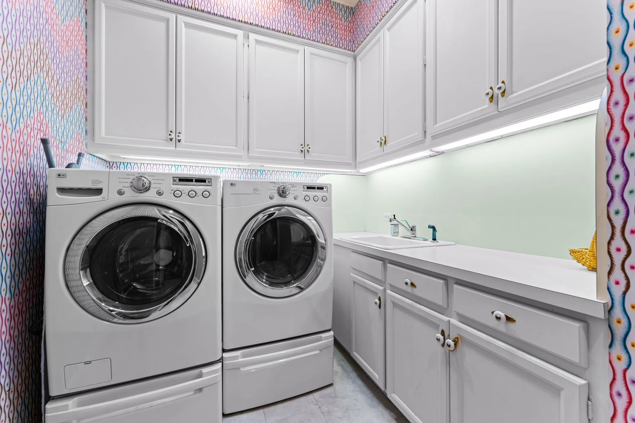 White cabinetry with gold-tone hardware, undermount sink, and a countertop with ample workspace