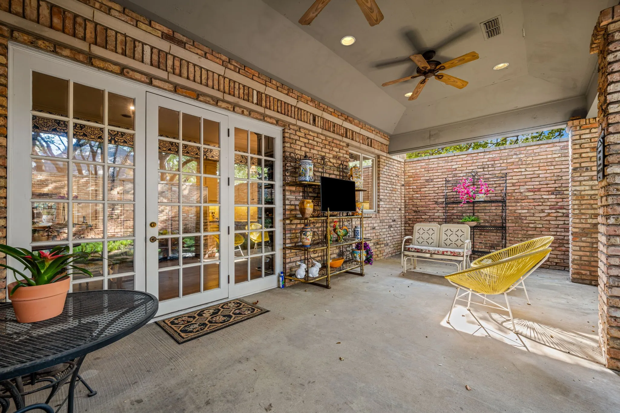 Covered patio featuring brick walls, a vaulted ceiling, recessed lighting, and dual ceiling fans