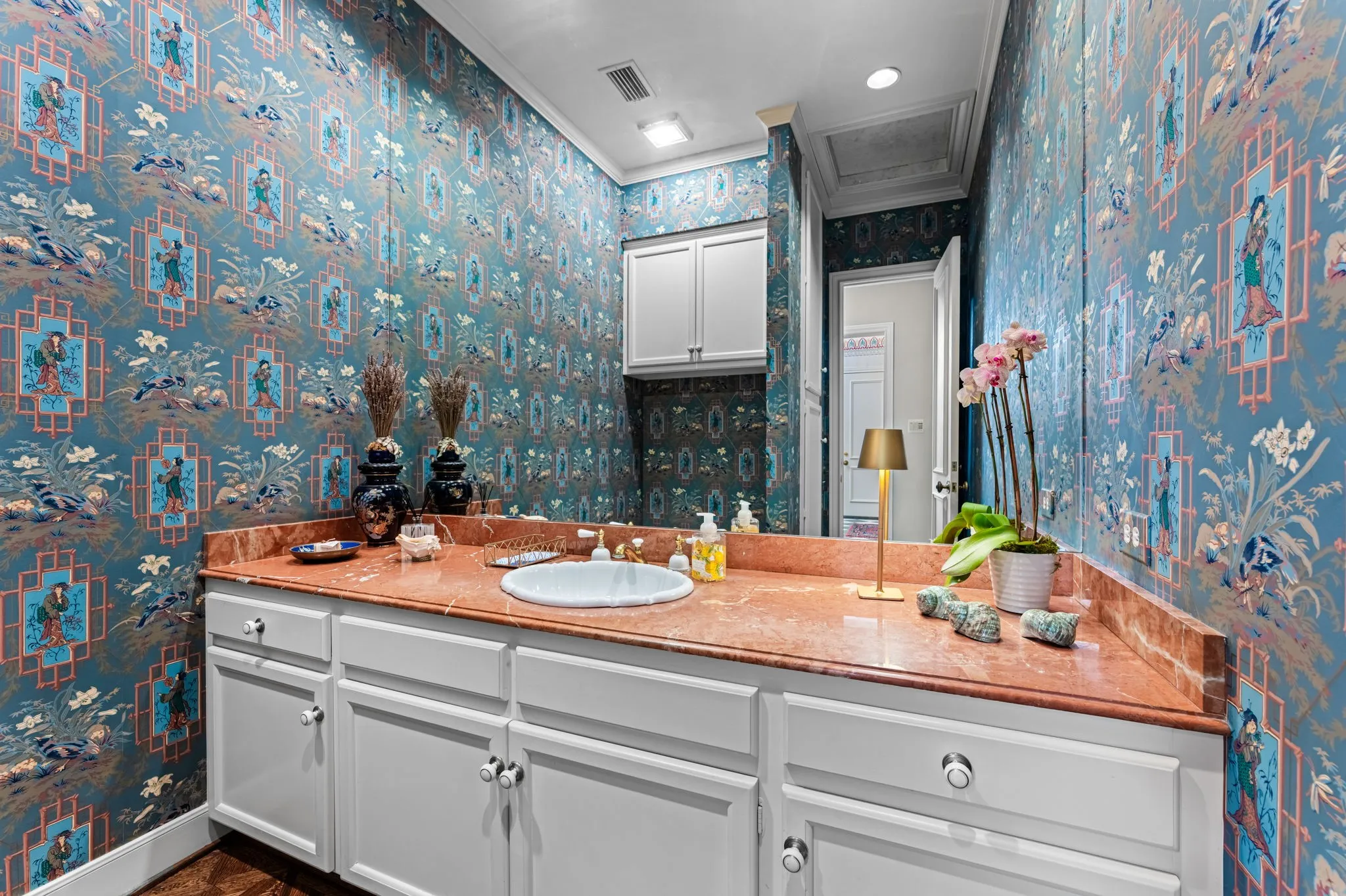 Beautiful half bathroom off the foyer with vanity with a single basin, a polished countertop, and under-cabinet storage