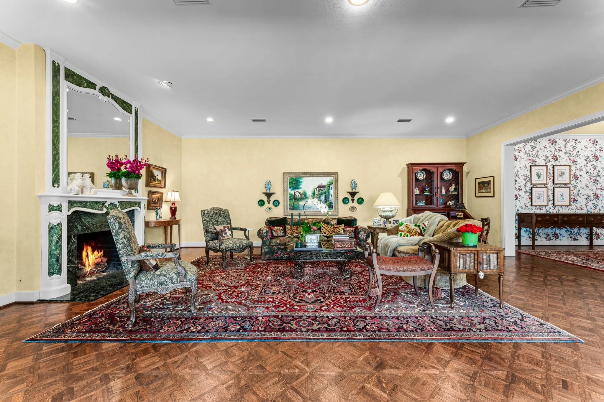 Hardwood parquet flooring, recessed lighting, and a prominent fireplace with a decorative green stone surround and white mantel
