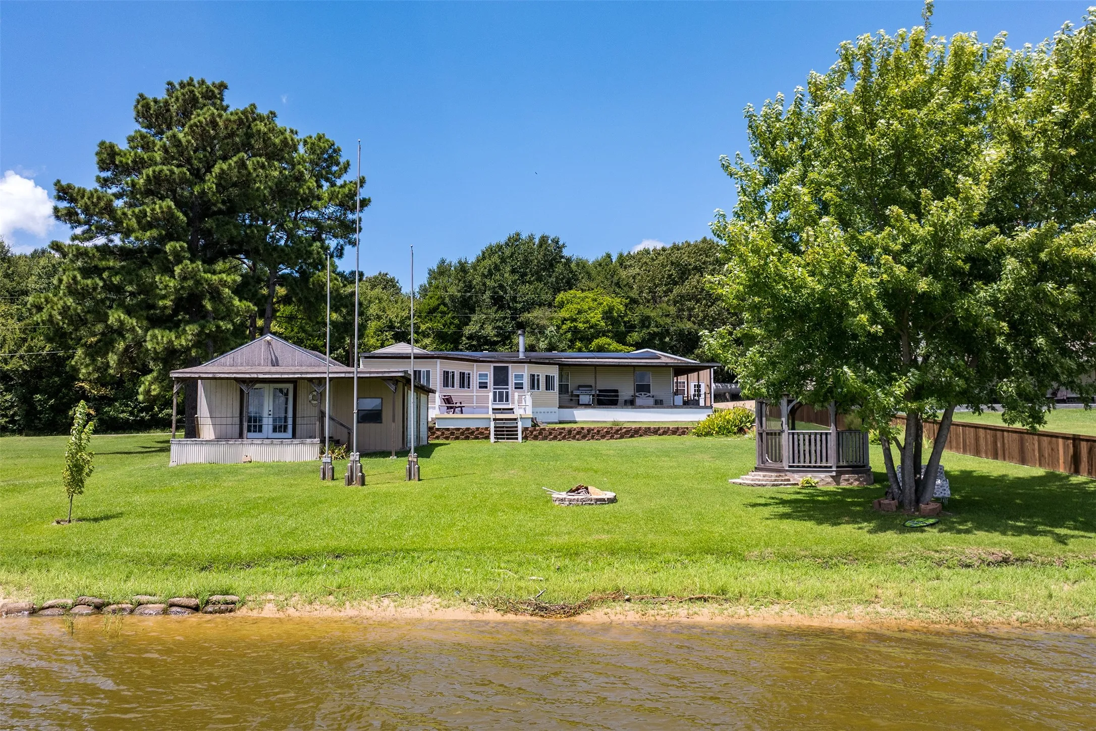Back of home with large storage shed with deck looking out to water.
