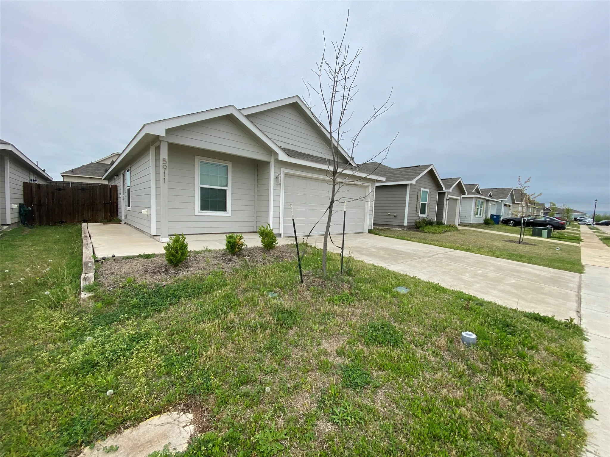 Single story home featuring a front yard, concrete driveway, fence, a residential view, and a garage