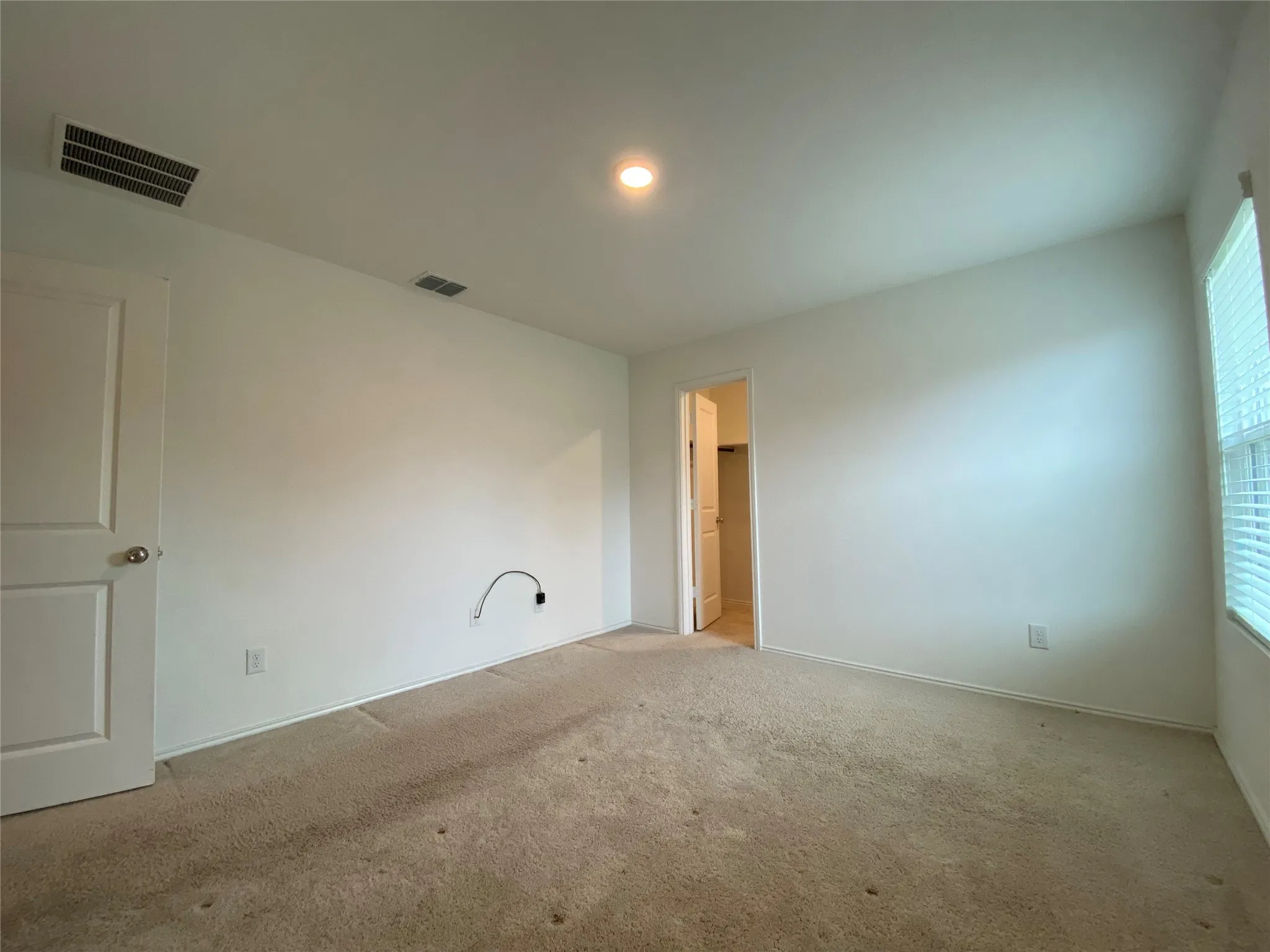Empty room featuring light carpet and visible vents