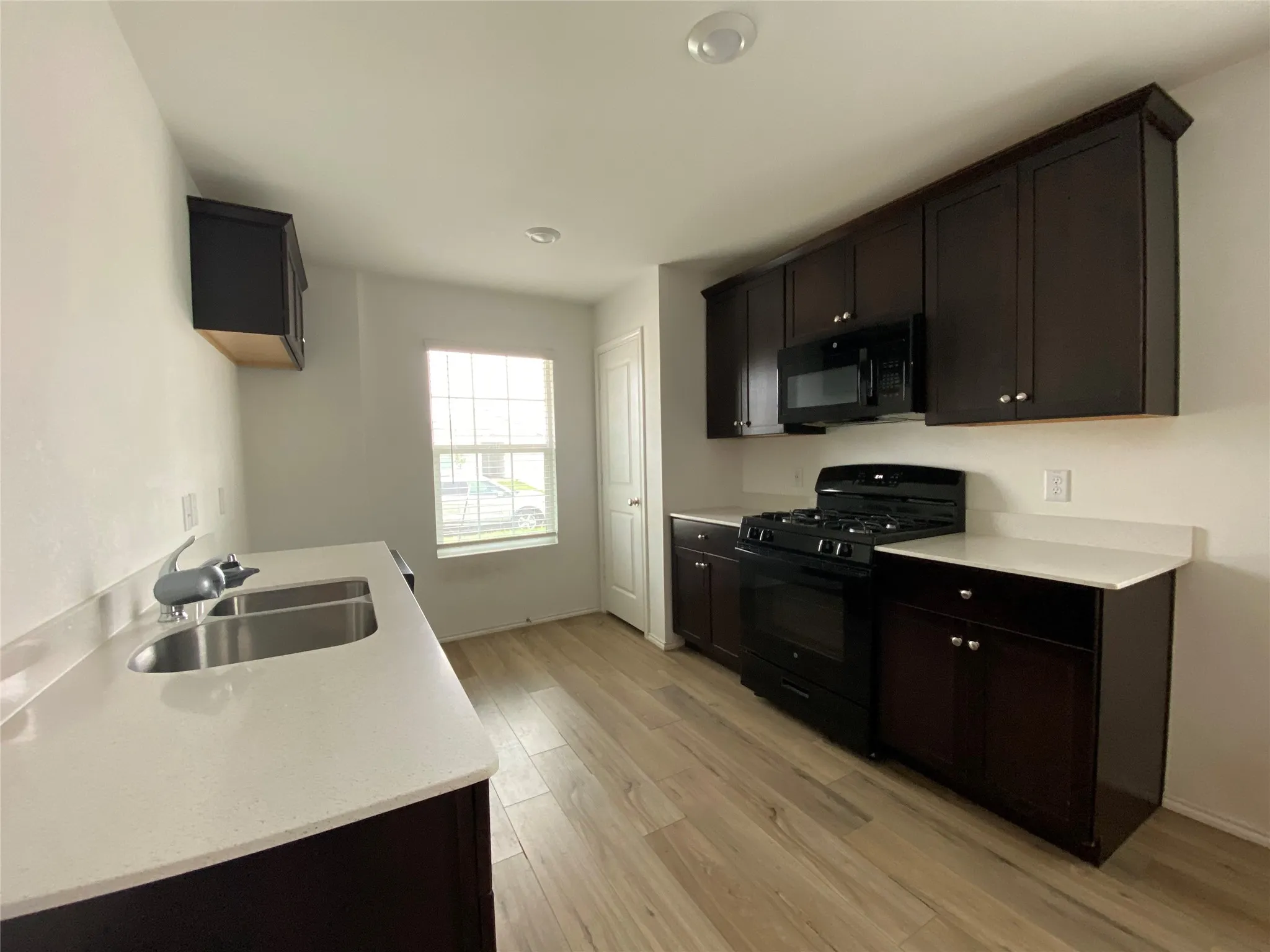 Kitchen featuring black appliances, light wood-style flooring, light countertops, and a sink