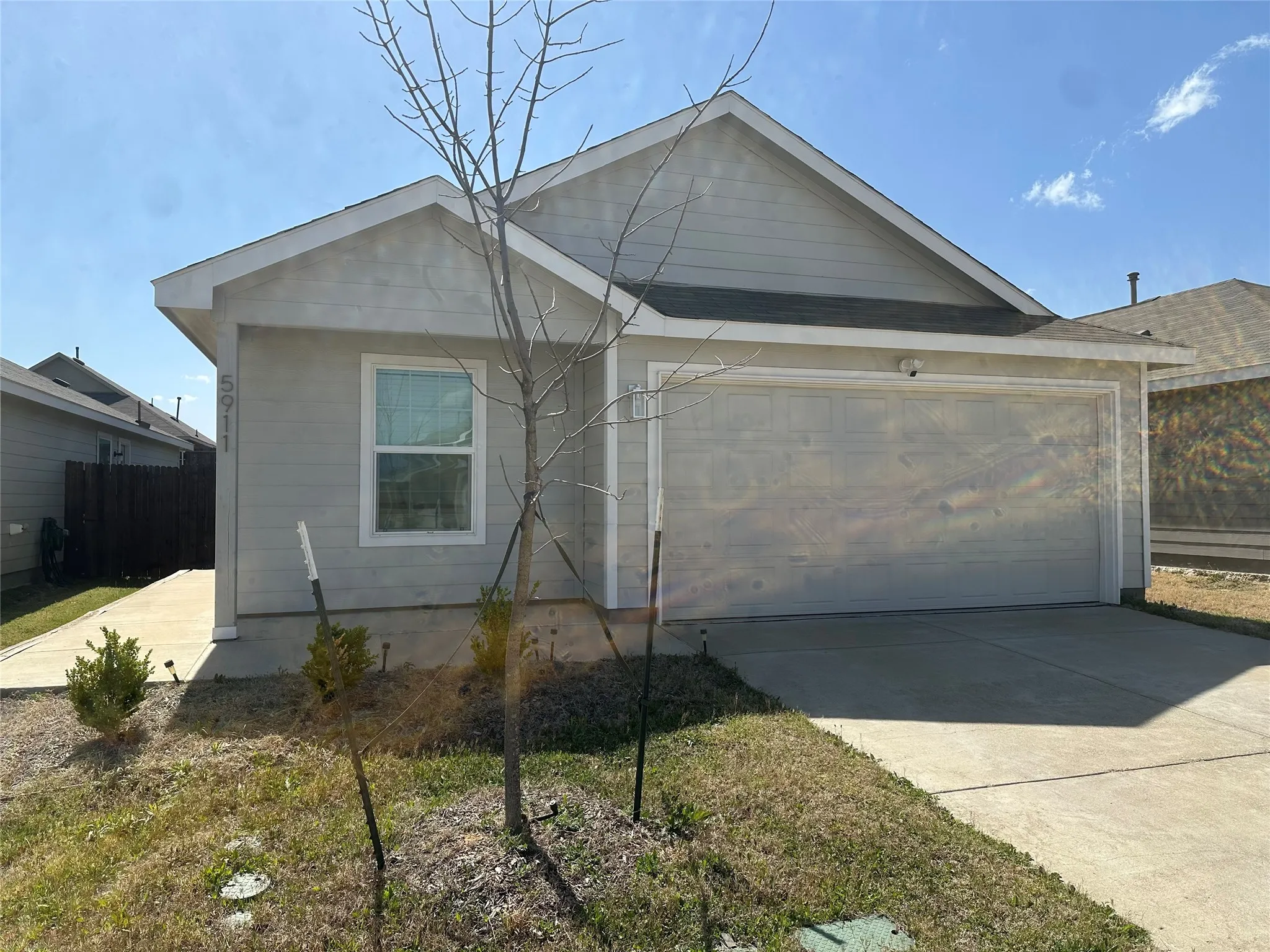 View of front of house featuring a garage, concrete driveway, and fence