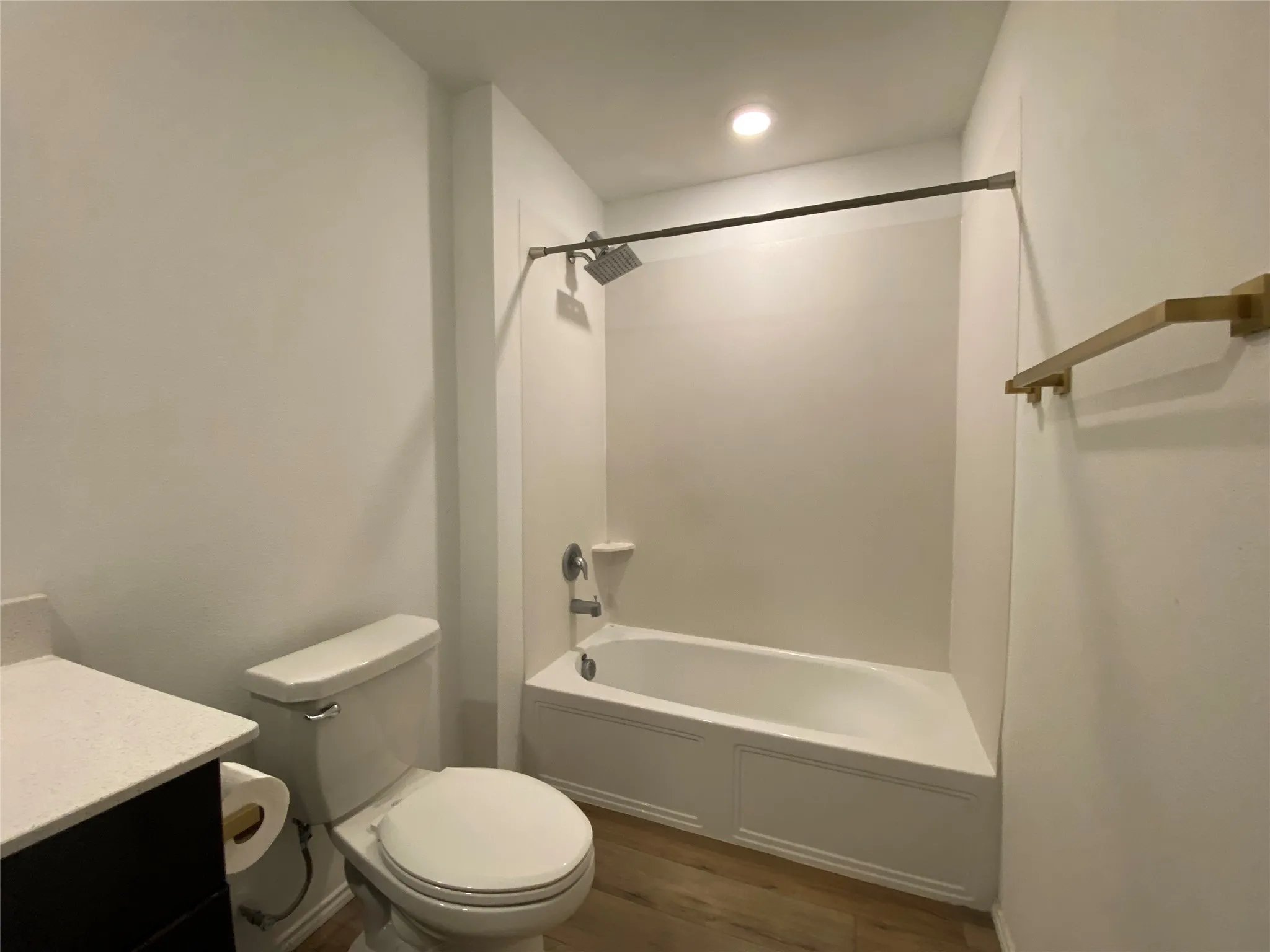 Full bath with toilet, vanity, washtub / shower combination, and wood finished floors