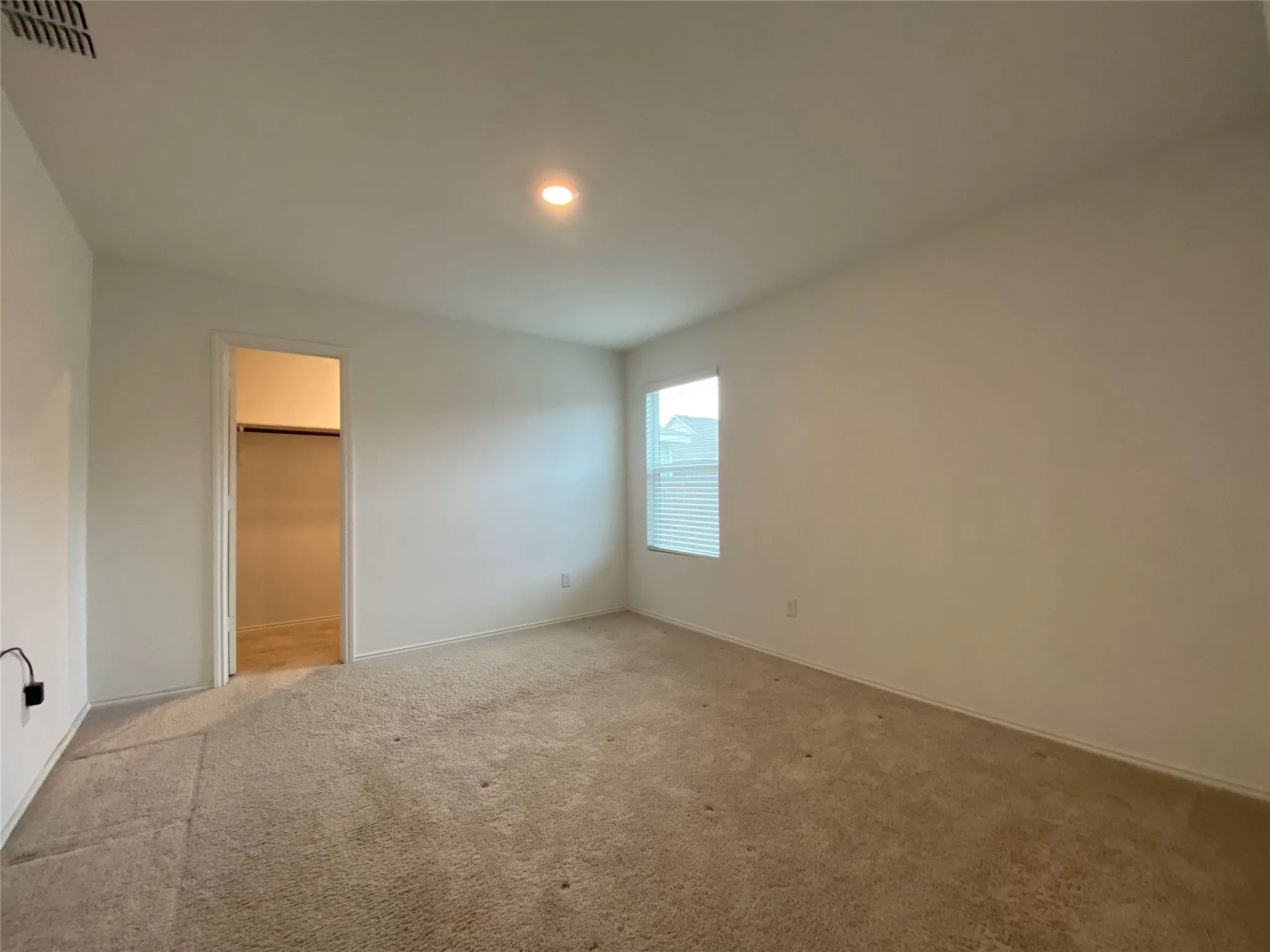 Unfurnished bedroom featuring baseboards, carpet flooring, visible vents, and a walk in closet