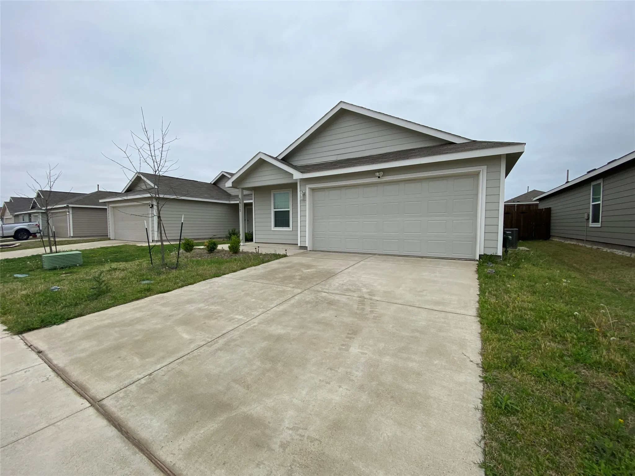 Ranch-style home with a front yard, an attached garage, and concrete driveway
