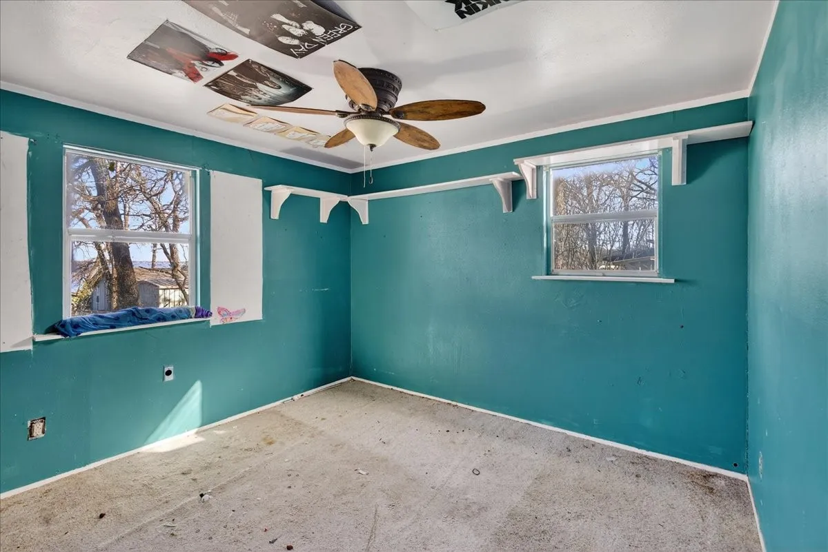 Bedroom with ceiling fan and windows for natural lighting.