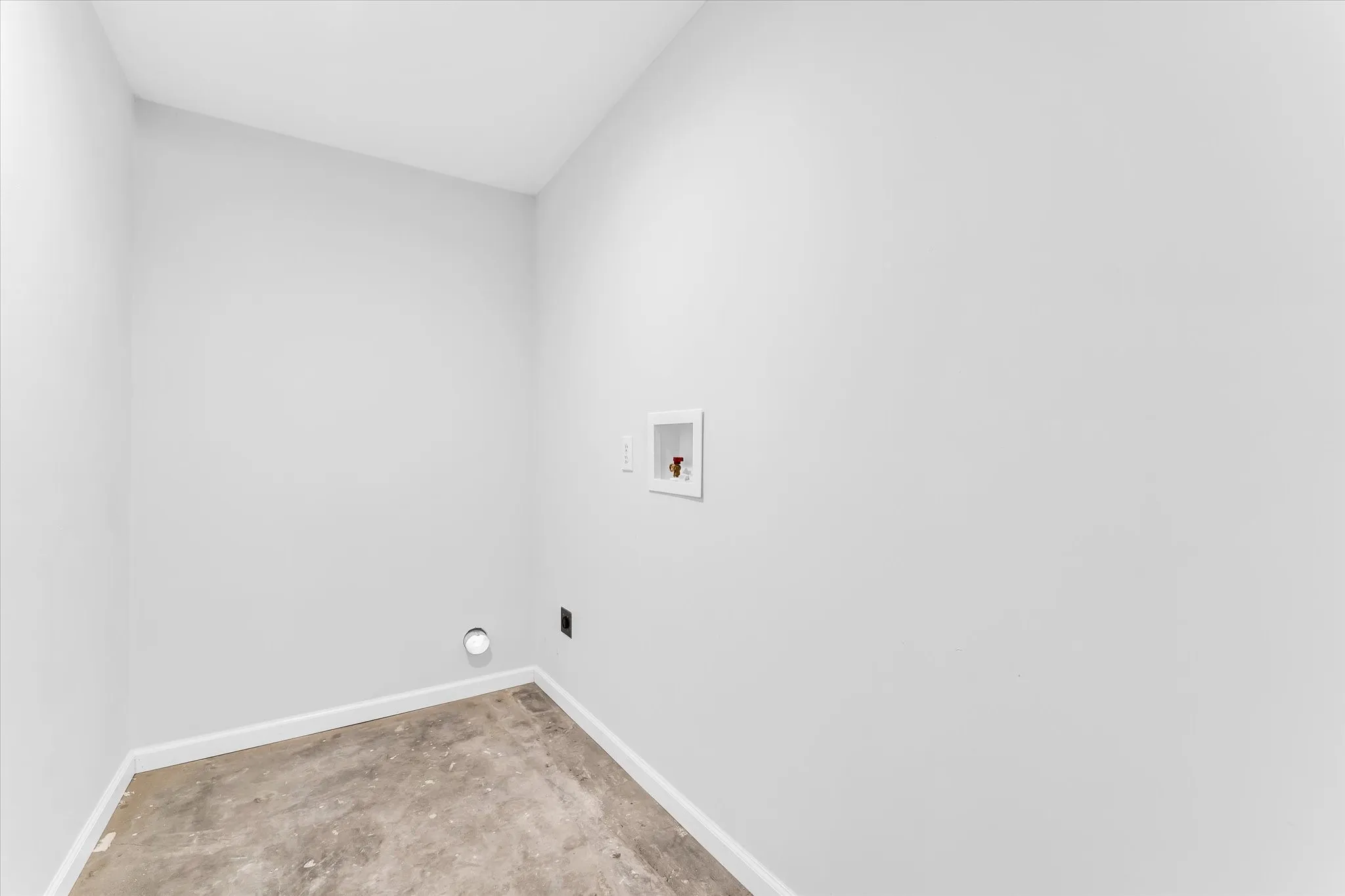 Dedicated utility space featuring light gray walls, white trim, and concrete flooring