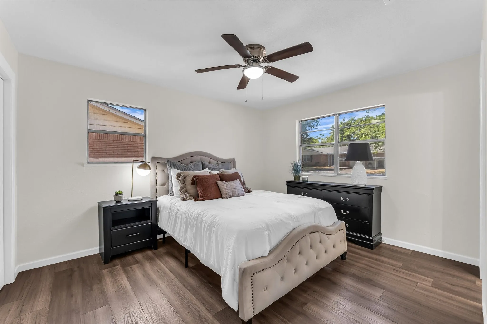 Wood-finish flooring throughout, complemented by light-colored walls and a ceiling fan with integrated lighting