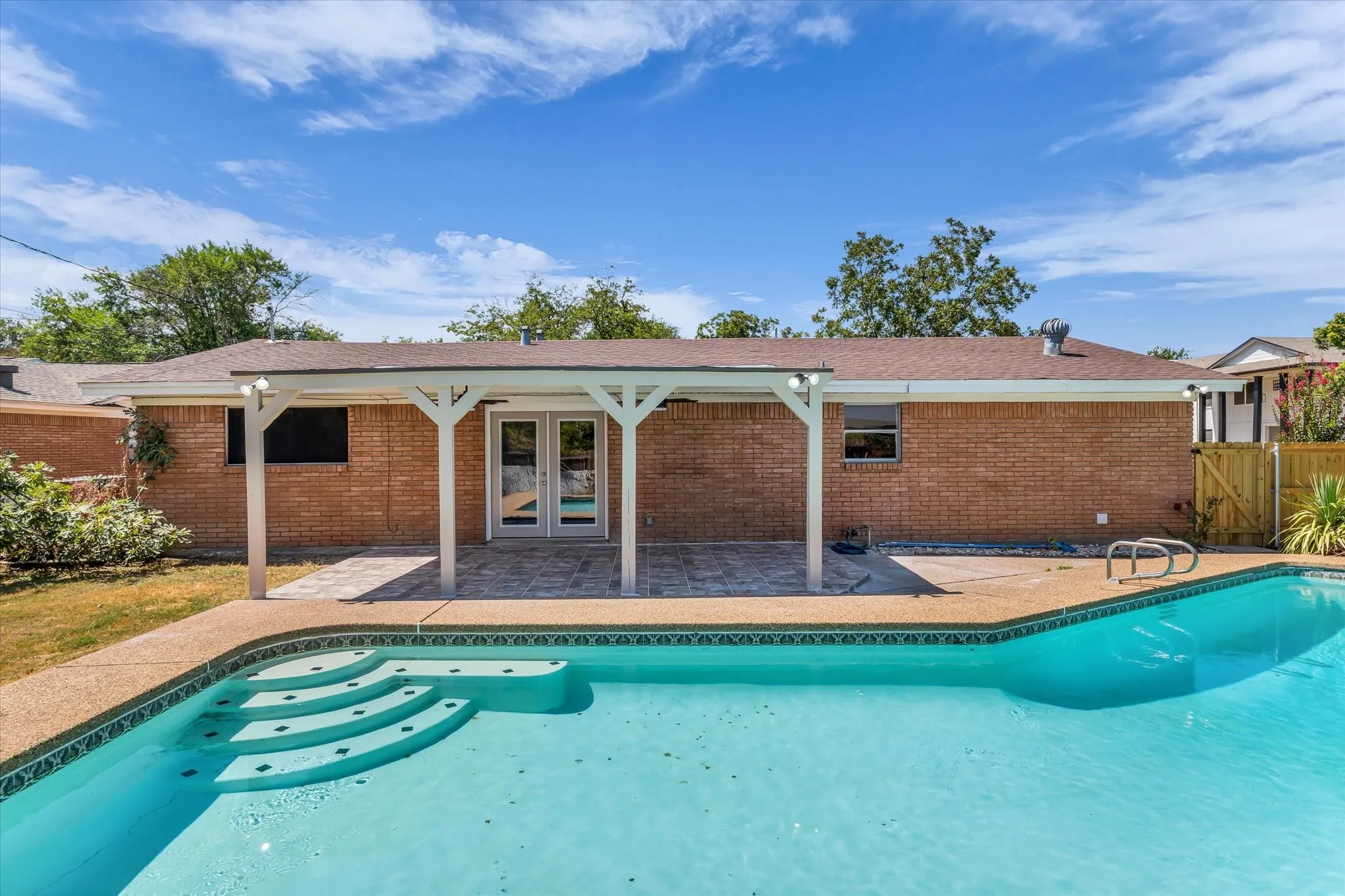 Brick exterior with a covered patio and a built-in swimming pool