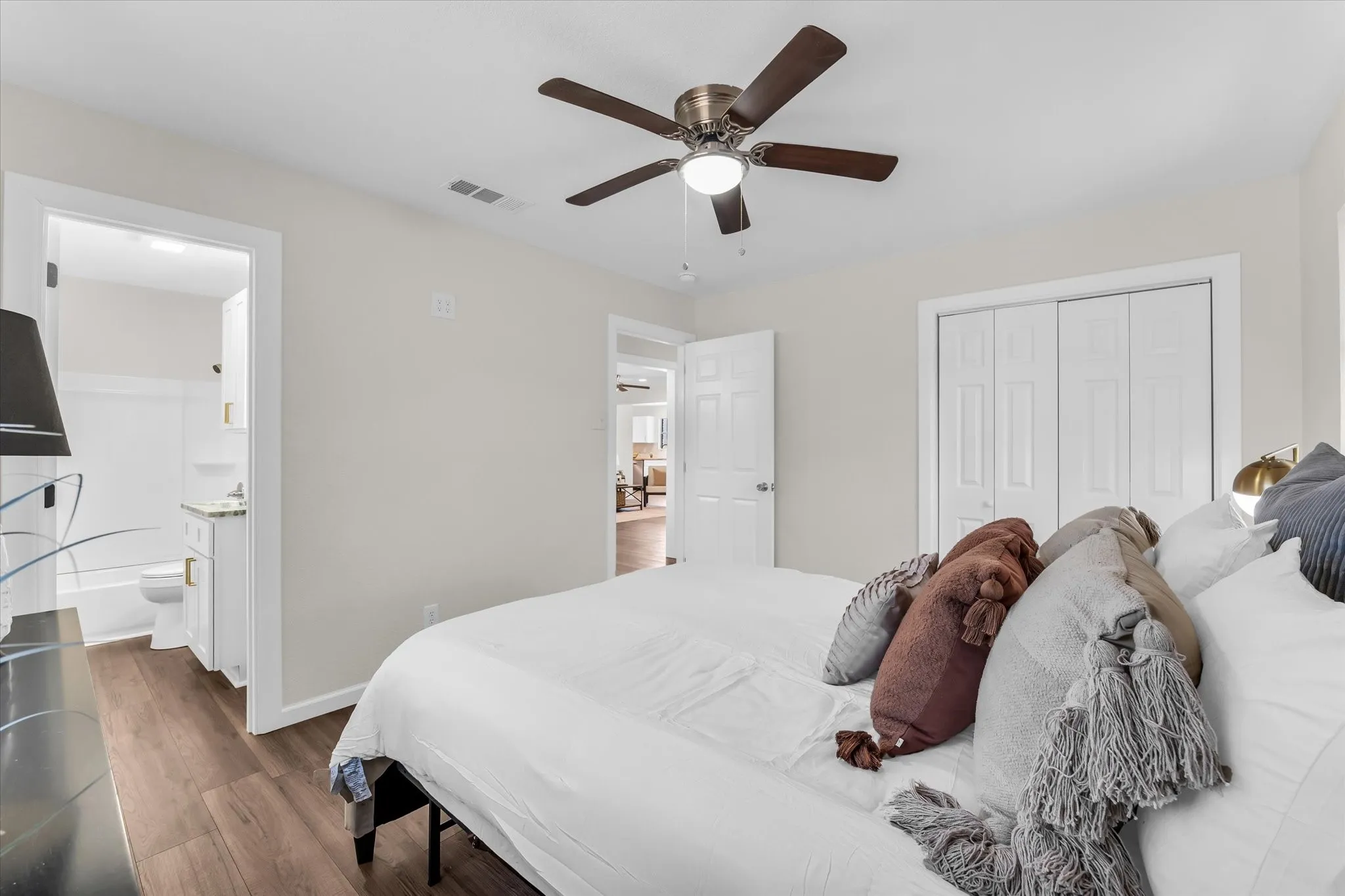 Wood-finish flooring, ceiling fan with integrated lighting, and white bi-fold closet doors