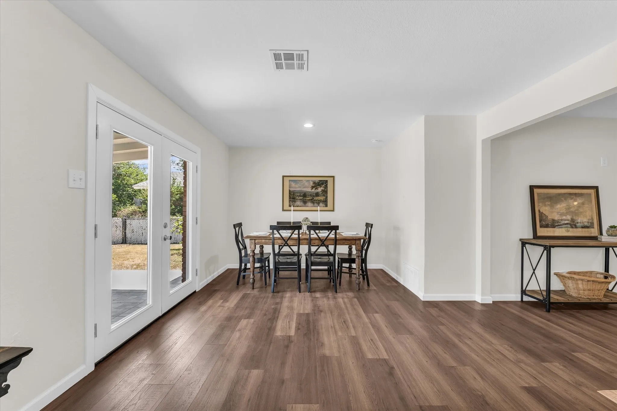 Wood-finish flooring throughout, white walls, recessed lighting, and white French doors with glass panels