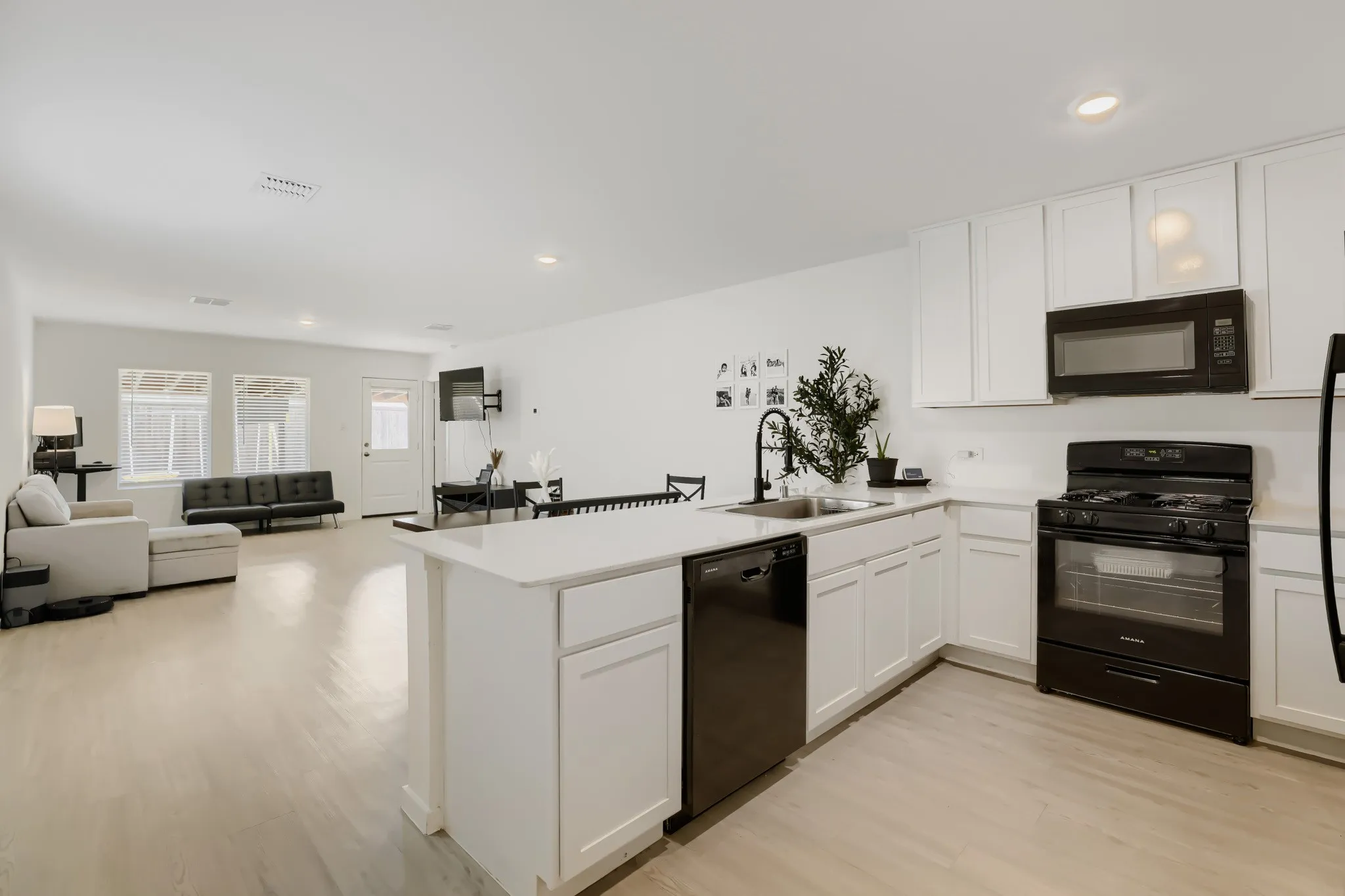 Kitchen featuring white cabinetry, light countertops, and black appliances