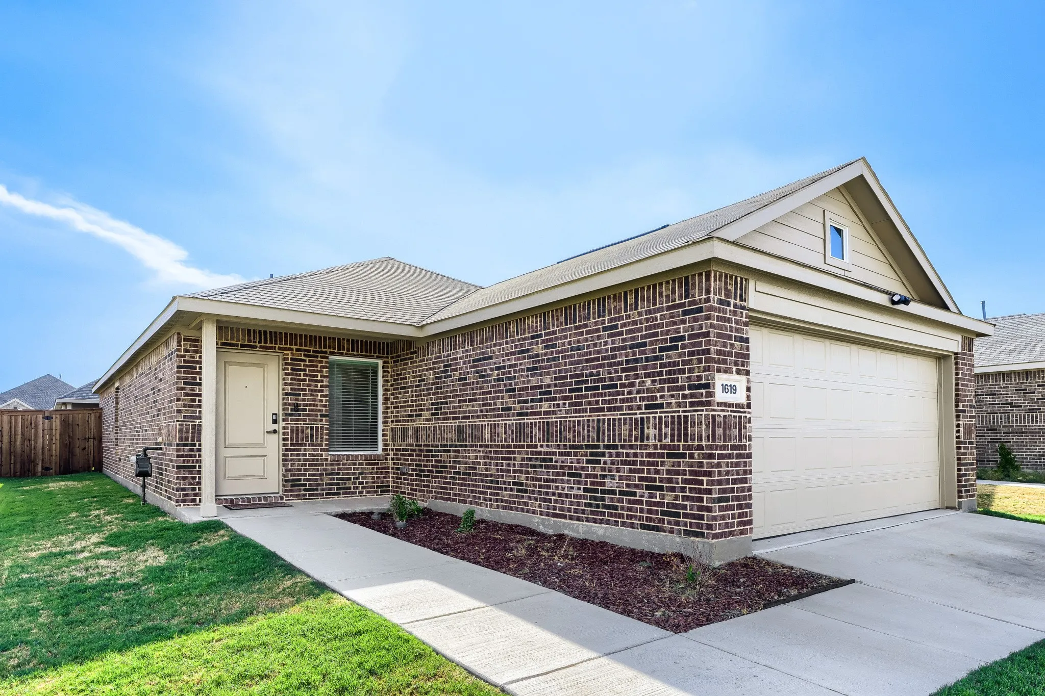 Brick exterior with an attached garage, covered entryway, and a fenced side yard